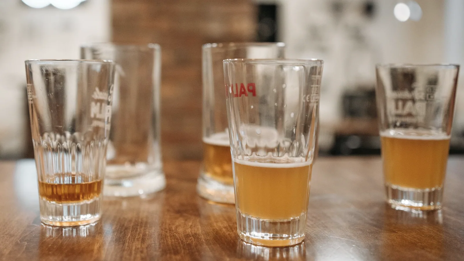 Verschillende glazen bier op een houten tafel, ter illustratie van alcohol en energiebalans