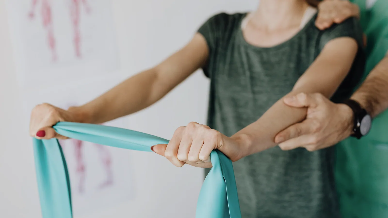 Fysiotherapeut begeleidt schouderoefeningen met een elastische weerstandsband