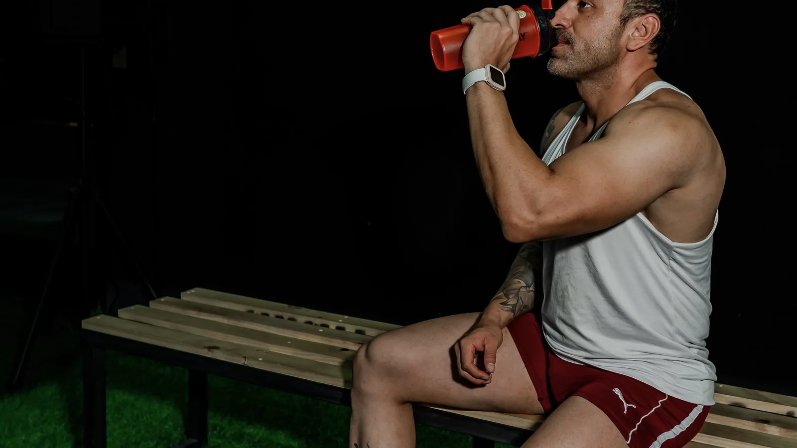 Sporter drinkt uit een shaker tijdens de voorbereiding op een fitnesssessie