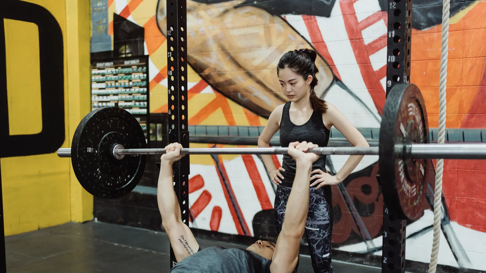 Sporter doet een bankdruk met een spotter in een fitnesscentrum