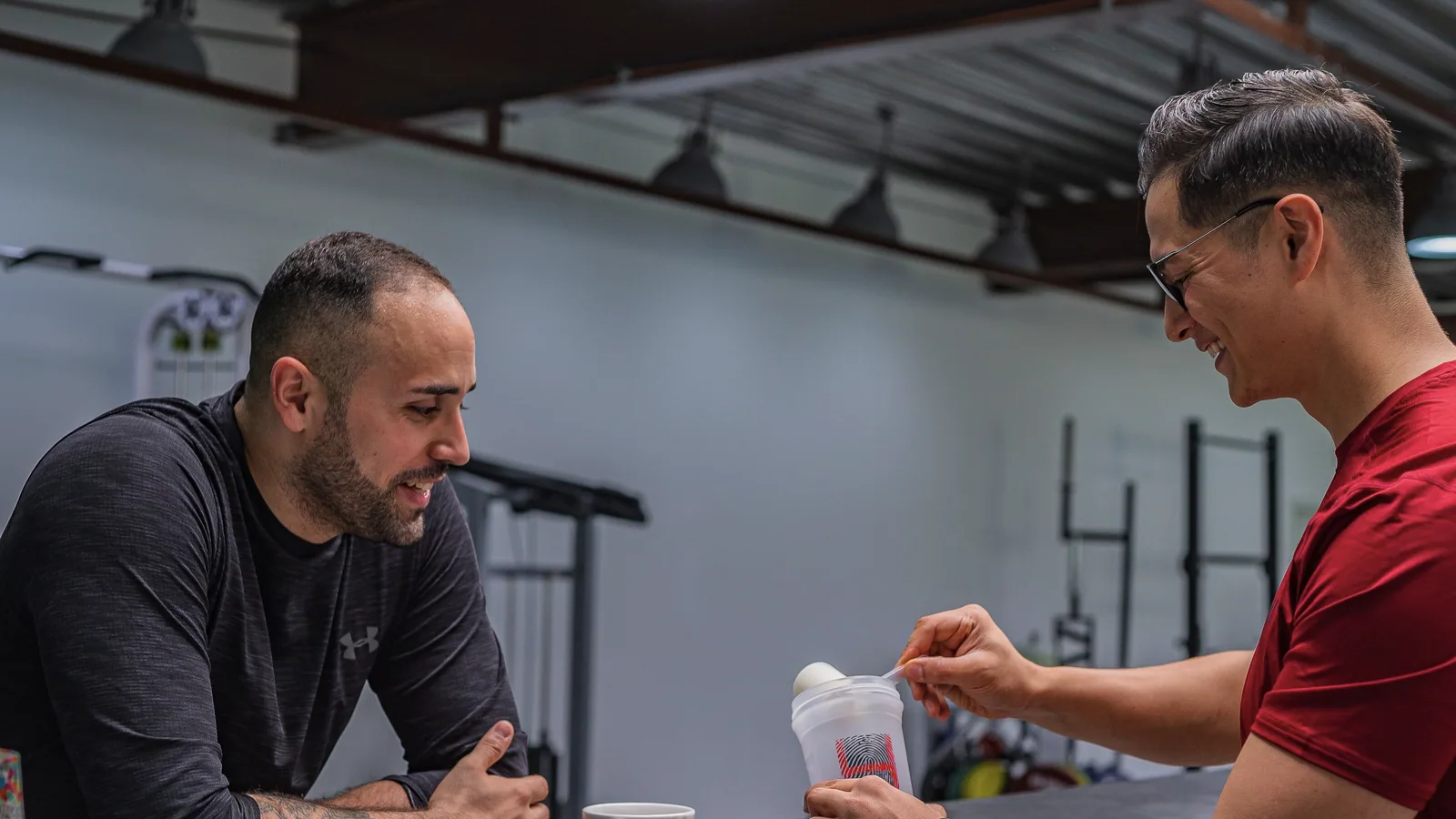 Twee sporters bereiden samen een eiwitdrank voor na hun training